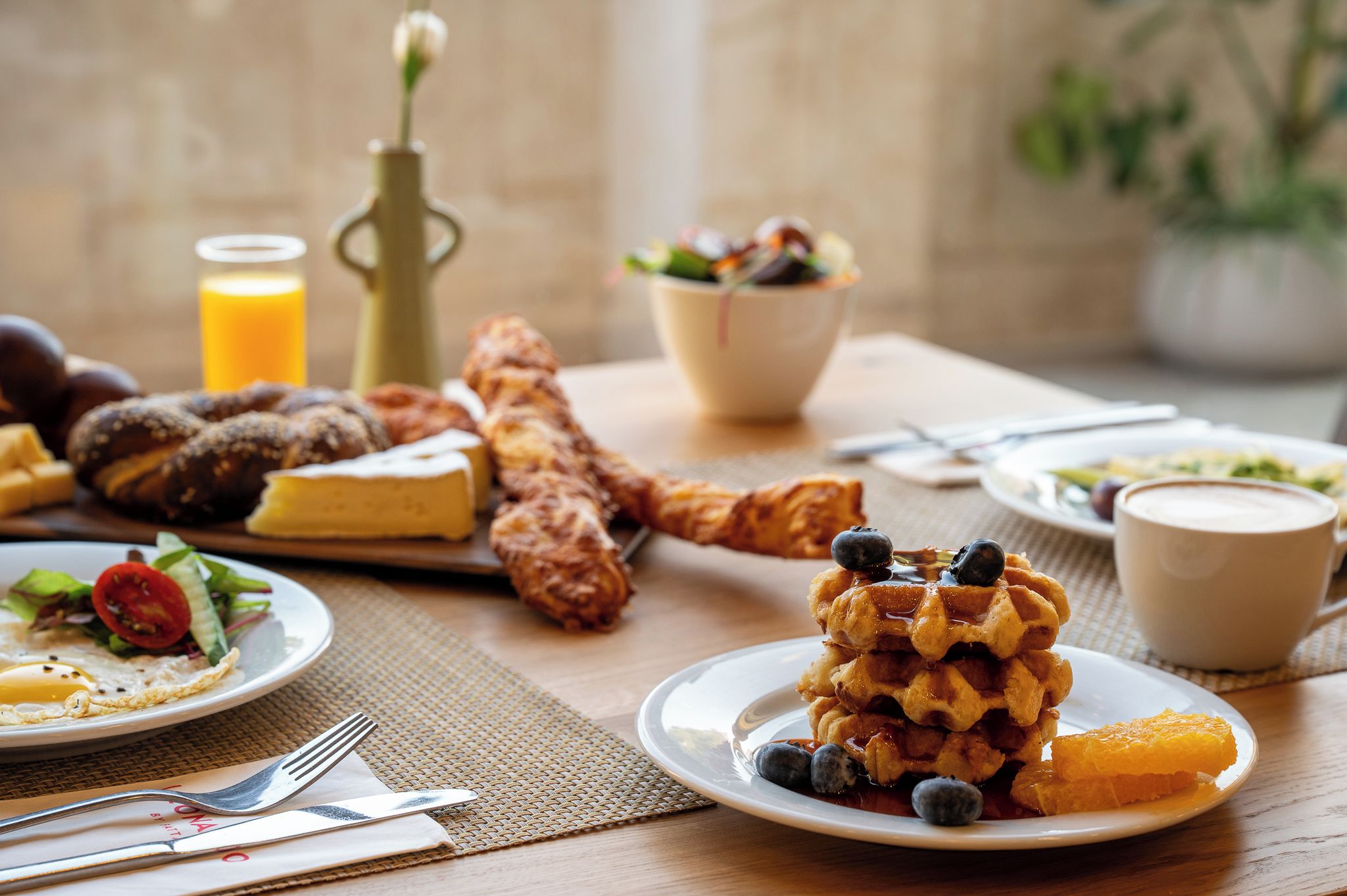 Un desayuno con waffles, huevos, tostadas y un bol de fruta.