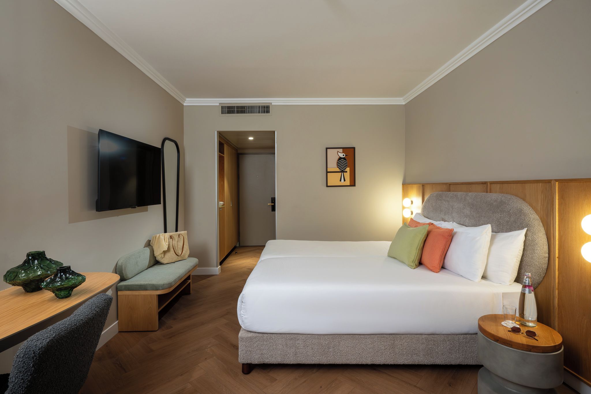Una camera d'albergo con un letto, un comodino, TV, area salotto e una porta che conduce a un'altra stanza.