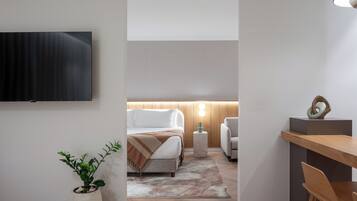 Een moderne hotelkamer met een bed, nachtkastje, lamp en een wandtelevisie.