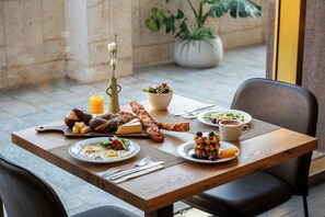 A dining table with breakfast items including eggs, toast, and a salad. - Leonardo Hotel Negev (Beersheba)