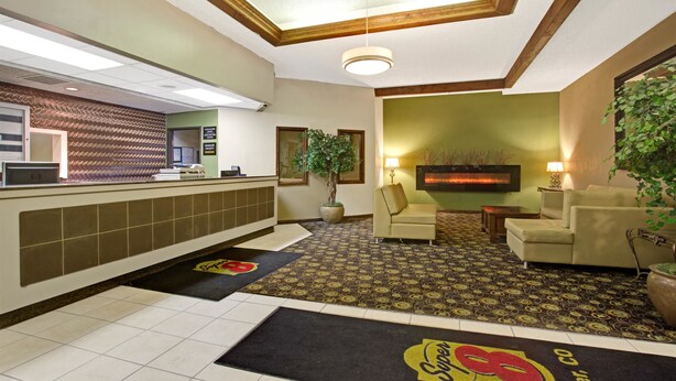 Un vestíbulo de hotel con mostrador de recepción, una planta grande en maceta, un sofá y una chimenea.