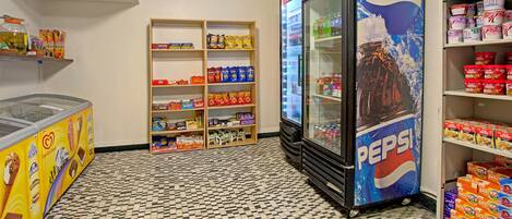 A vending machine area with a Pepsi refrigerator, shelves stocked with snacks, and a checkered floor.