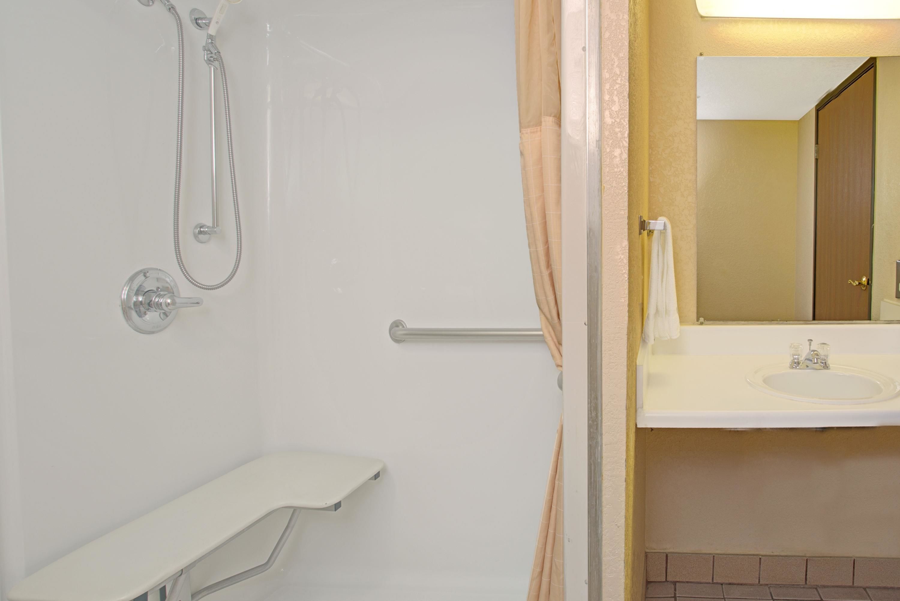 A bathroom with a shower, a sink, and a mirror.