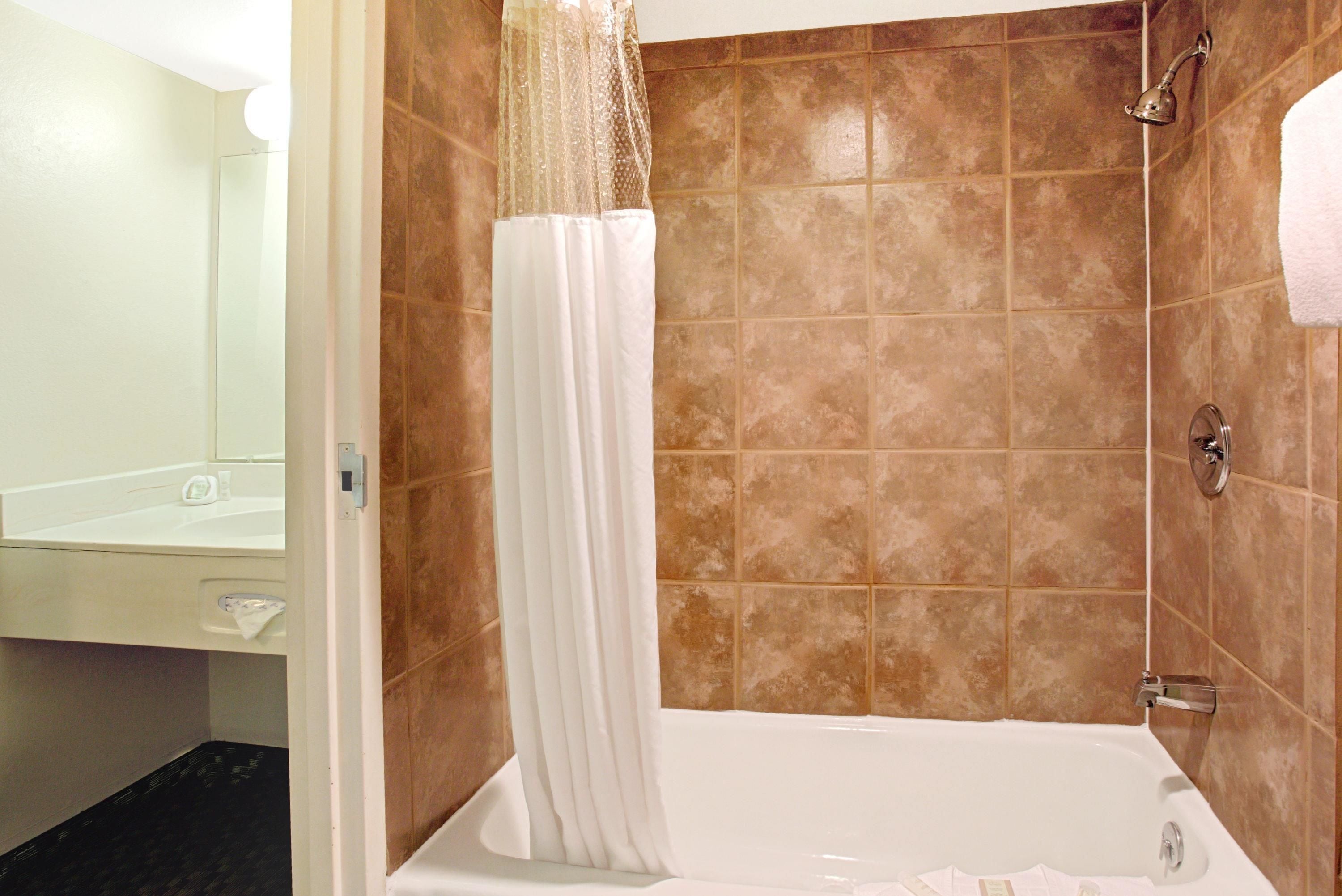 A bathroom with a bathtub, a shower, and a mirror.