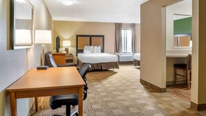 Een hotelkamer met een bed, bureau, stoel en een klein tafeltje.