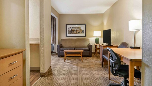 Een hotelkamer met een bank, een televisie, een bureau met stoel en een lamp.