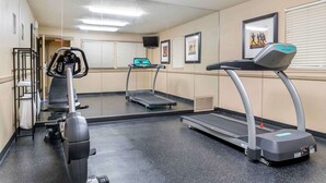 Een sportschool met loopbanden, een hometrainer en een roeiapparaat.