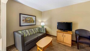 A hotel room with a sofa, a television on a wooden cabinet, a small table, and a lamp. - Extended Stay America Suites Oklahoma City Northwest (Oklahoma City)