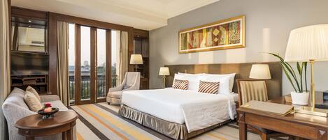 A hotel room with a large bed, a sofa, a desk, and a TV.