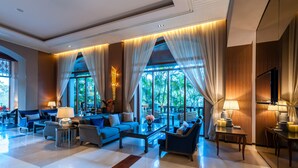 A spacious living room with large windows, a sofa set, a coffee table, and a TV. - Chatrium Hotel Royal Lake Yangon (Yangon)
