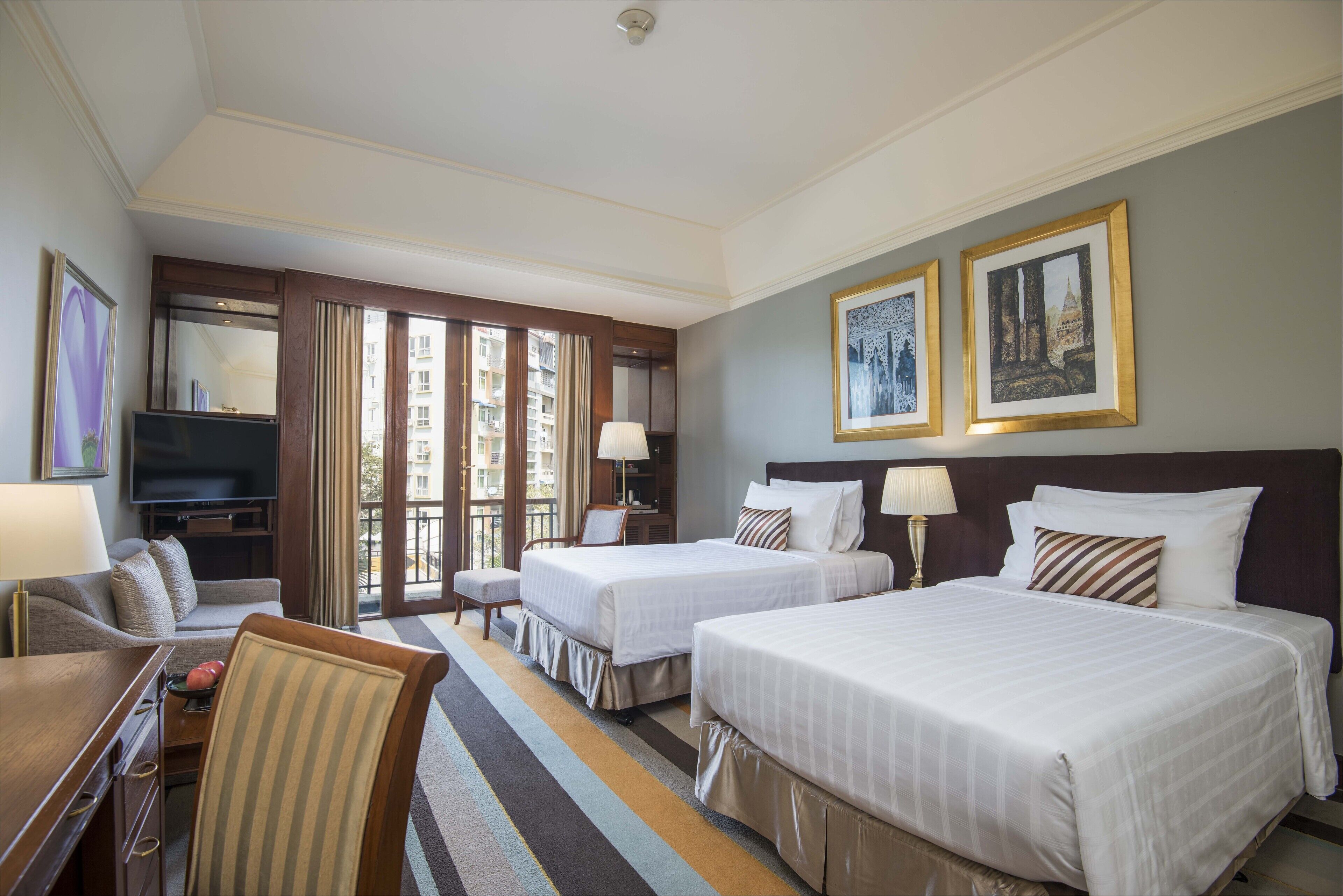 A hotel room with two beds, a TV, a desk, and a chair.