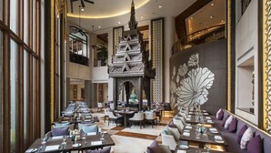 A spacious restaurant with high ceilings, a central decorative structure, and a checkered floor. - Chatrium Hotel Royal Lake Yangon (Yangon)