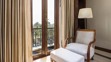 A room with a view of a balcony, a chair, and a lamp.
