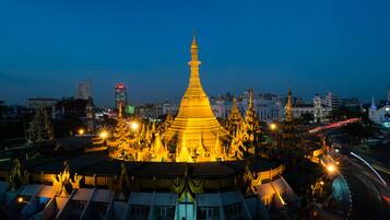 A large, illuminated pagoda with a golden spire, surrounded by traditional buildings and a busy street with light trails.
