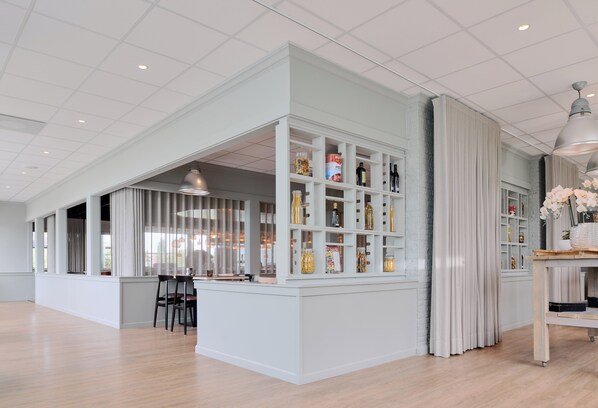 Una habitación amplia con una zona de bar integrada, que cuenta con estantes llenos de botellas y copas.
