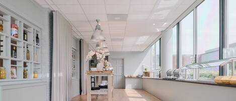 A modern kitchen with white cabinetry, a wooden countertop, and a large window providing natural light.