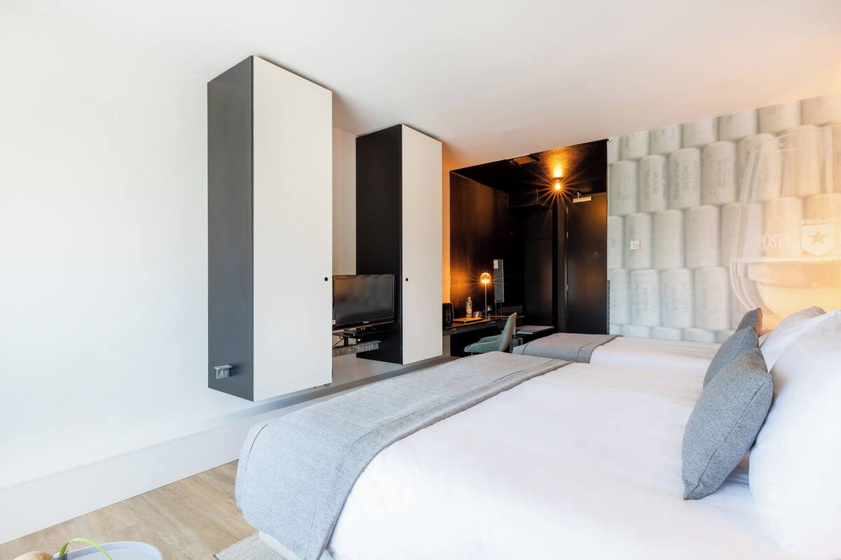 Ett modernt hotellrum med en stor säng, ett skrivbord, en tv och ett väggmonterat skåp.