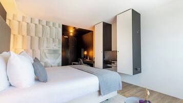 A modern hotel room with a large bed, a desk, a TV, and a wardrobe.
