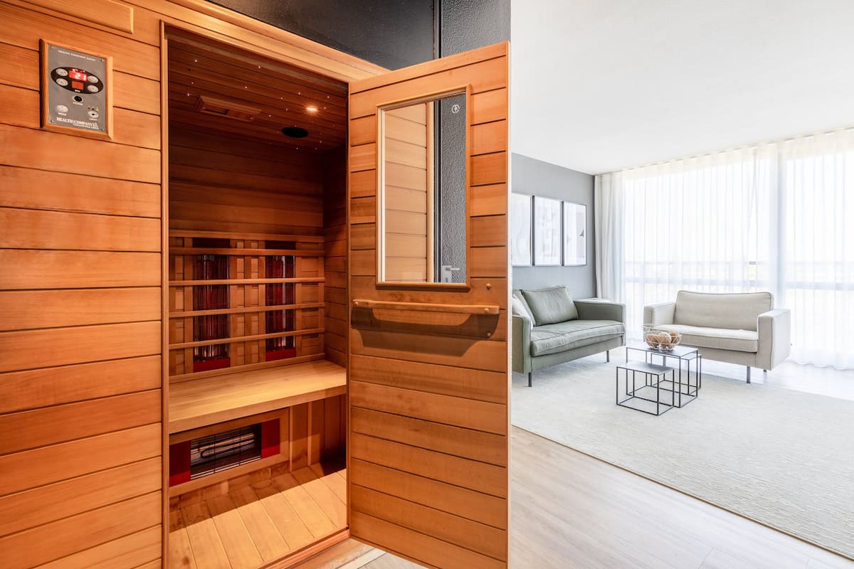 Een sauna met houten wanden en planken, een spiegel en een bedieningspaneel.