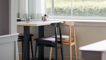 A dining area with a table, chairs, and a window with a view of greenery.