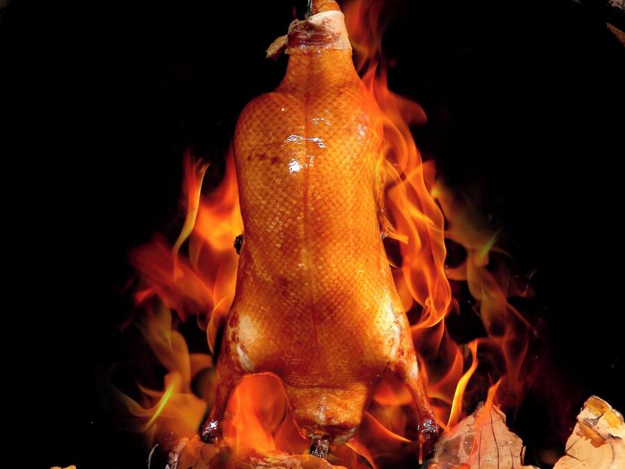 Ein gebratenes Schwein hängt über dem Feuer in einem Backofen aus Ziegeln.