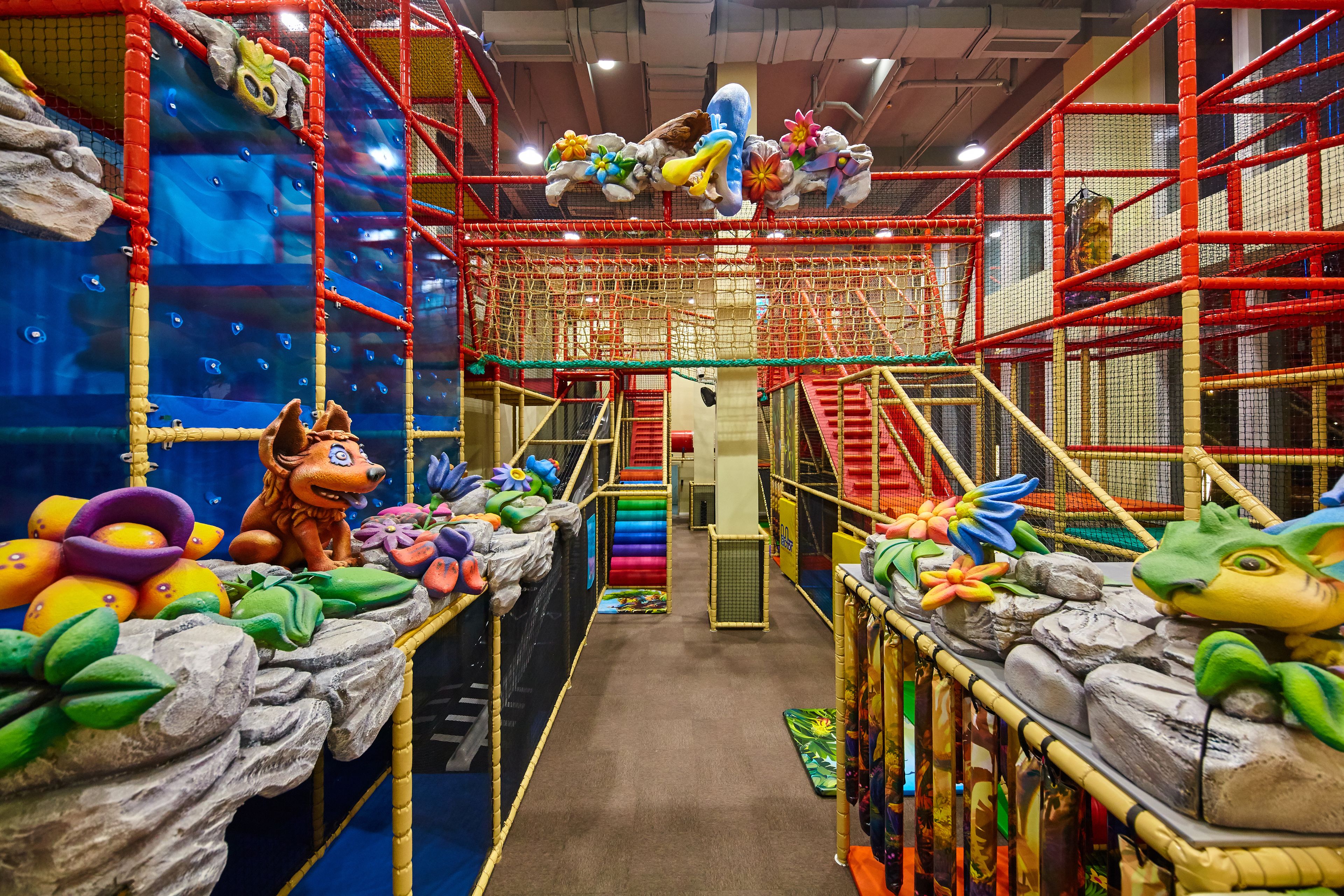 Espaço de recreação coberto com estruturas de escalada, escorregadores e diversos brinquedos.