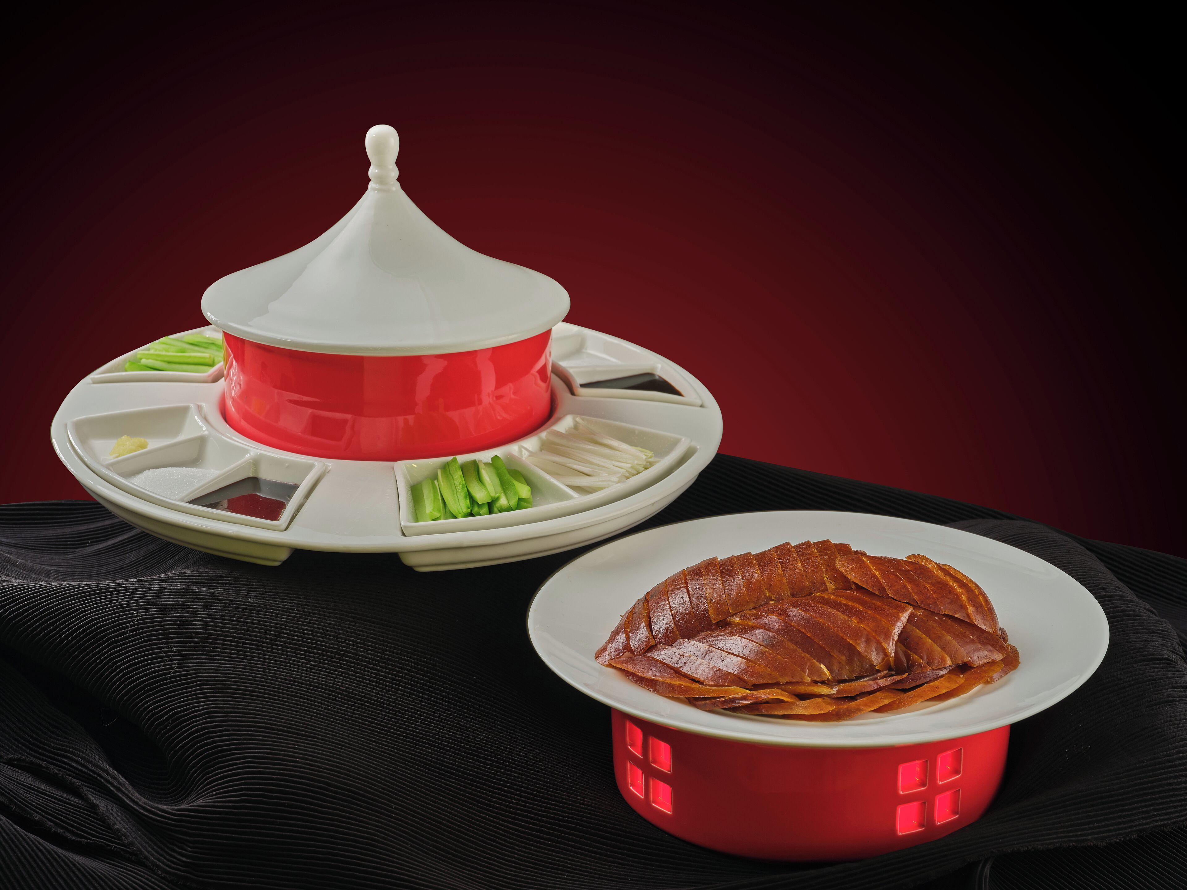 A table with a red and white food serving station and a plate with sliced meat.