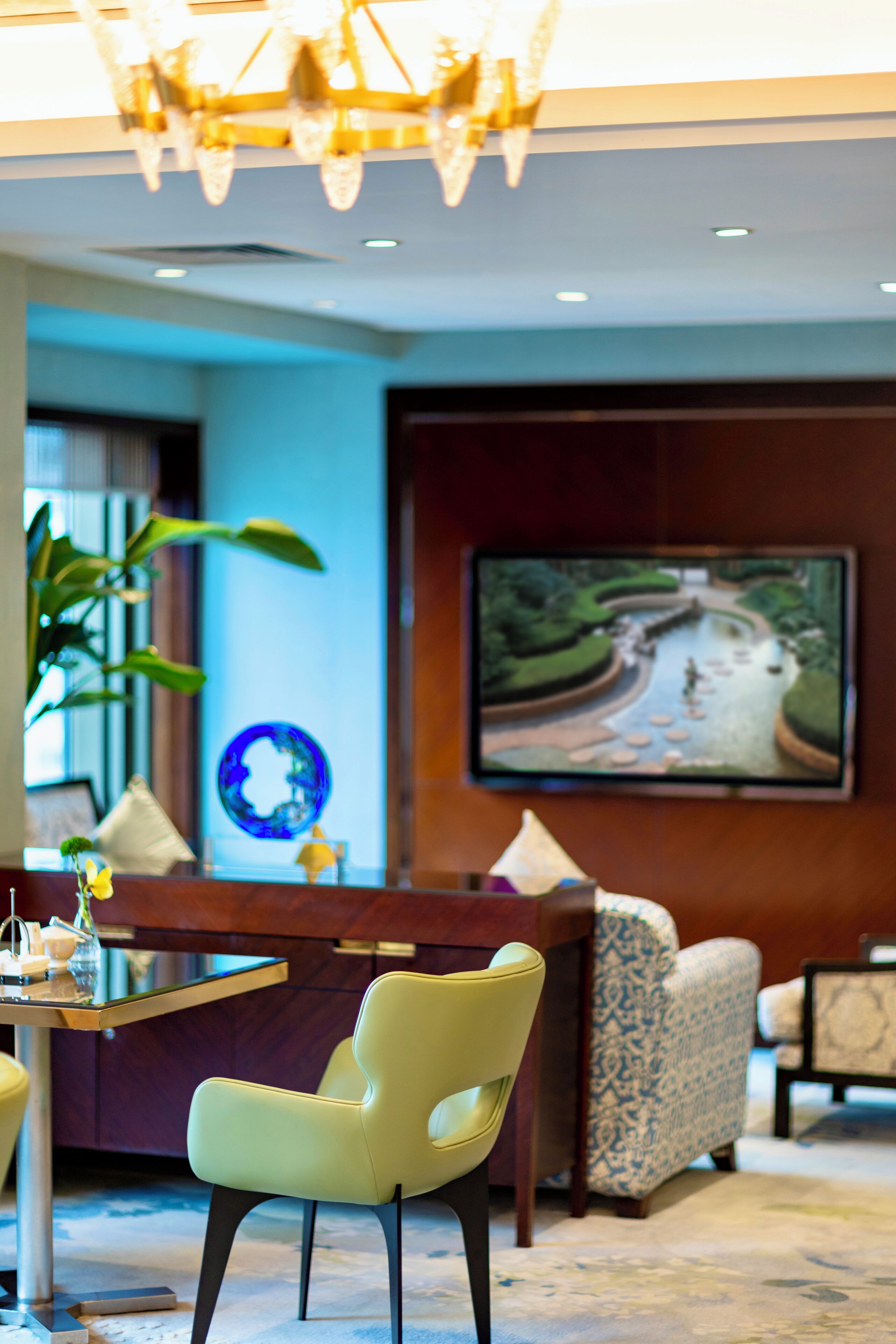 A modern lobby with a reception desk, seating area, and a large TV screen displaying a scenic landscape.