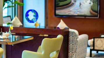 A modern lobby with a reception desk, seating area, and a large TV screen displaying a scenic landscape.