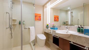 A modern bathroom with a glass-enclosed shower, a white toilet, a sink with a marble countertop, and a large mirror.