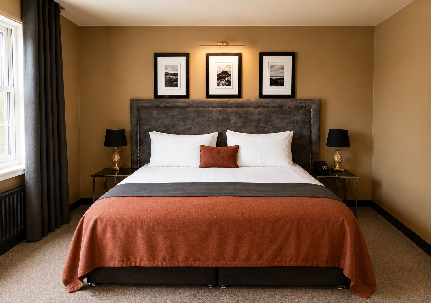 A hotel room with a large bed, two bedside tables with lamps, and three framed pictures on the wall.