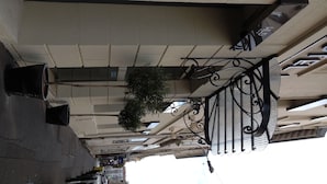 A corridor with a ceiling-mounted sign, a hanging plant, and a metal railing. - Hôtel le Dauphin (Puteaux)