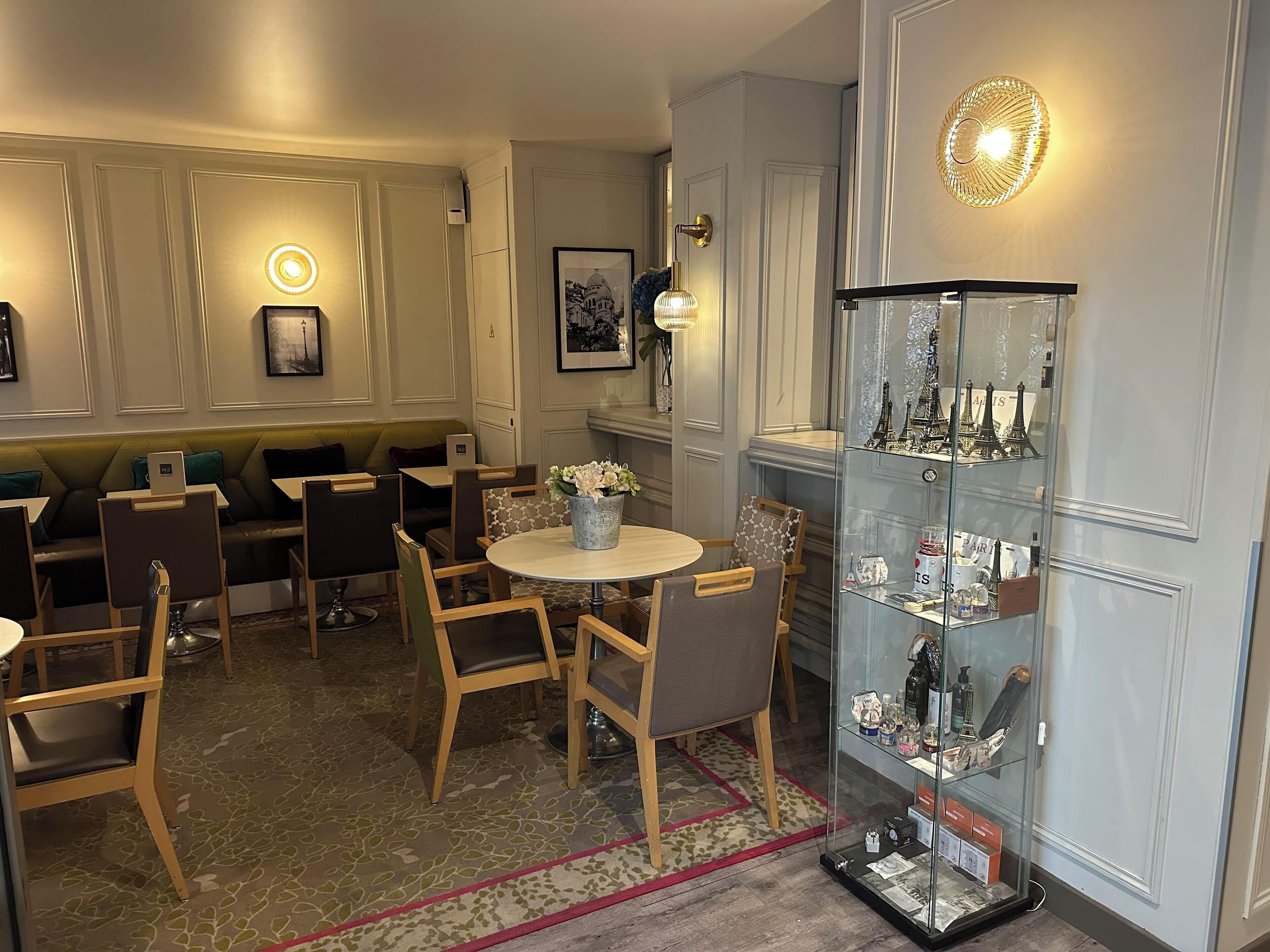 A dining area with a round table, chairs, a glass display case with souvenirs, and a wall-mounted light fixture.