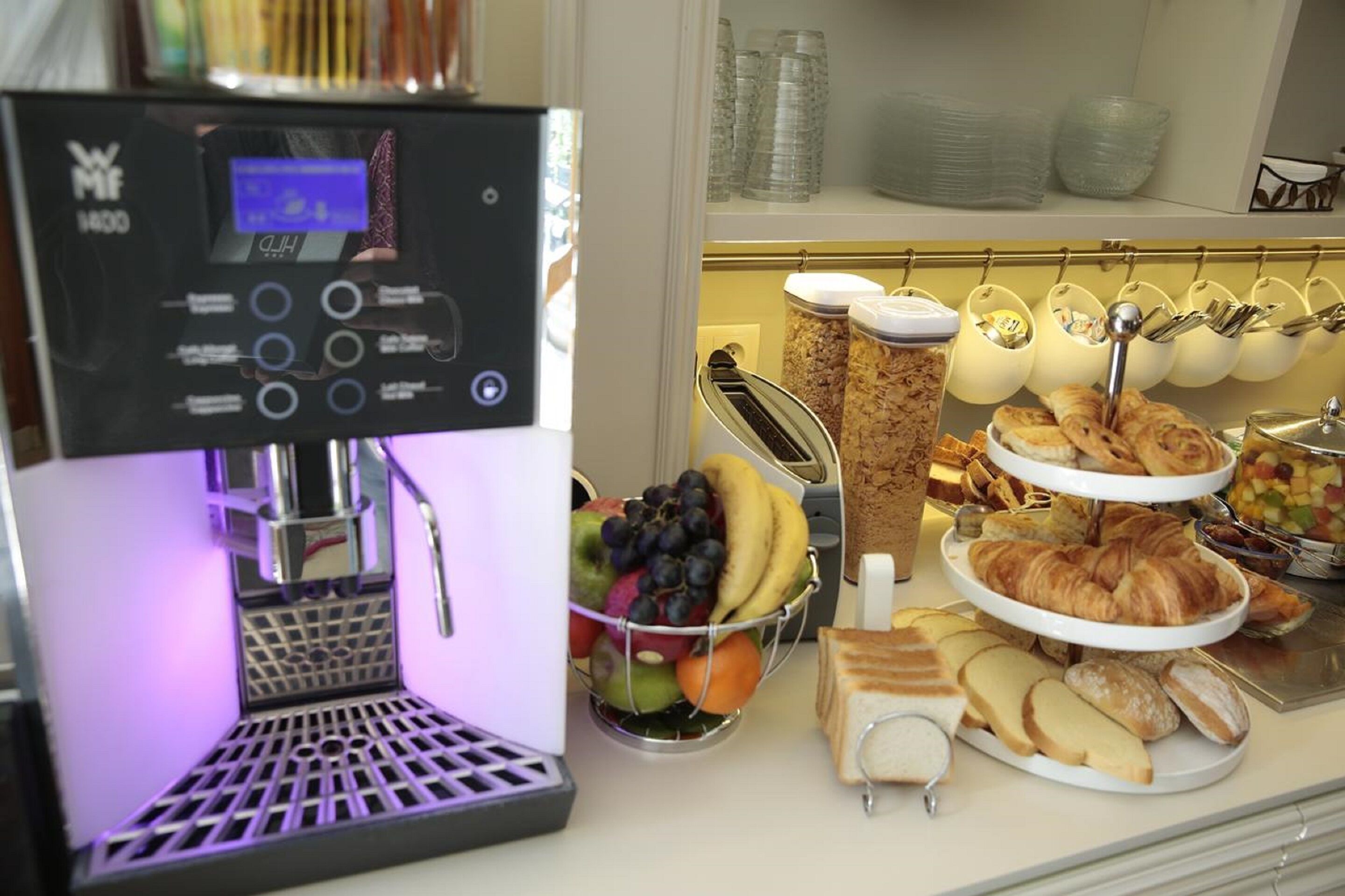 A coffee machine, a fruit bowl, and a variety of pastries and sandwiches.