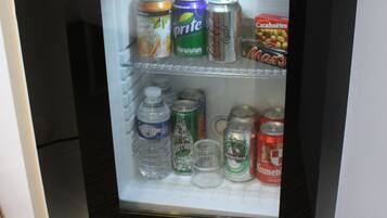 Un refrigerador pequeño con bebidas y un microondas encima.