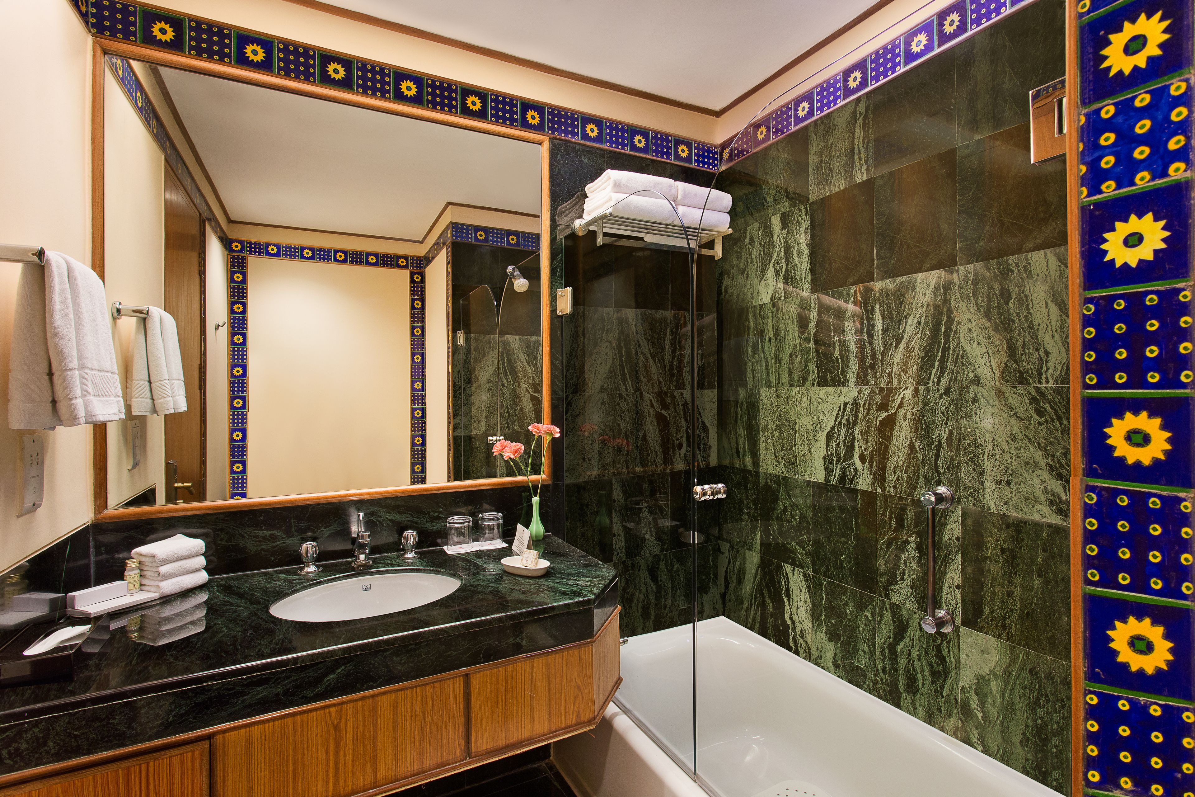 Casa de banho com lavatório de mármore preto, banheira branca e chuveiro com porta de vidro.