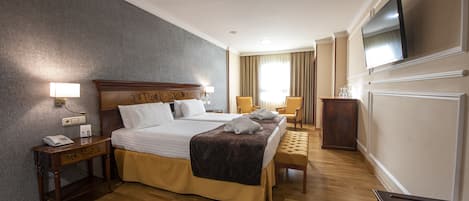 A hotel room with a large bed, bedside tables, a TV, and a wooden bench.