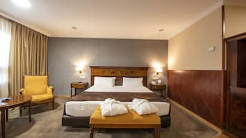 Una habitación de hotel con una cama grande, una mesita de noche, una silla y una pequeña mesa.