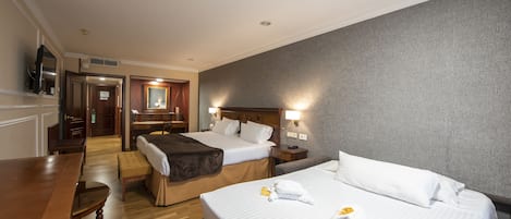 A hotel room with two beds, a wooden desk, and a television.