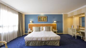 Habitación de hotel con una cama grande, dos mesitas de noche, un escritorio y una silla.