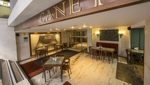 Un hall de hotel con piso de mármol, muebles de madera y un gran letrero que dice 'CANEY'.