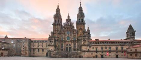 Una catedral histórica con dos torres destacadas y una cúpula central, rodeada por un patio.