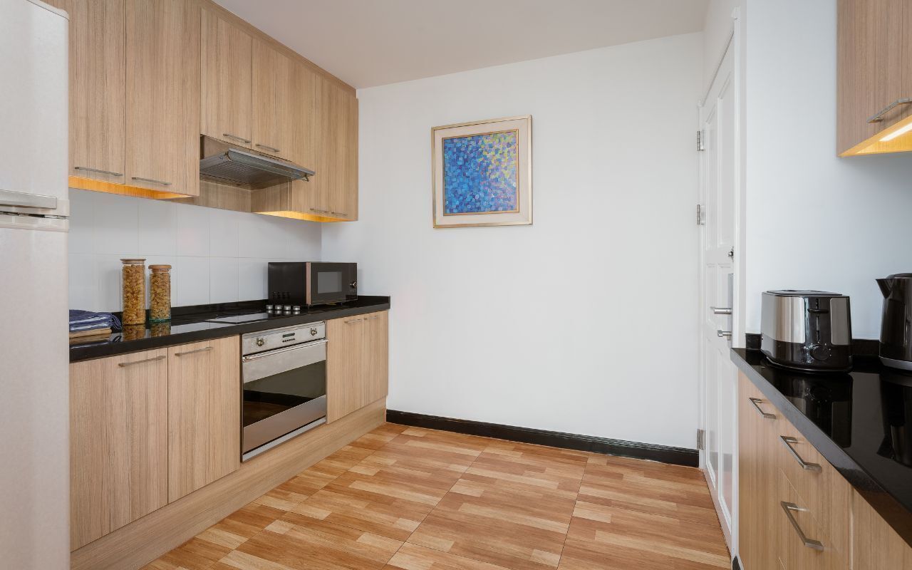 Eine moderne Küche mit Holzausstattung, einer Mikrowelle, einem Backofen und einer Kaffeemaschine.
