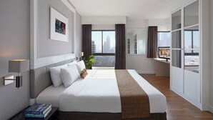 Een moderne hotelkamer met een groot bed, uitzicht op de stad, een bureau en een kledingkast.