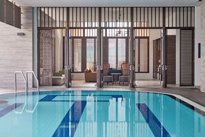 A swimming pool with clear water, surrounded by a modern interior with wooden slats, a sofa, and a table. - Somerset Park Suanplu Bangkok (Bangkok)