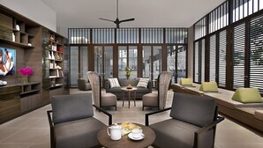Een moderne zithoek met een bank, fauteuils, een salontafel en een boekenkast.