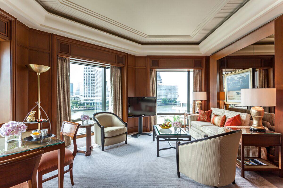 Ein Hotelzimmer mit großem Fenster, Flachbildfernseher, Sofa, Couchtisch und Schreibtisch mit Lampe.