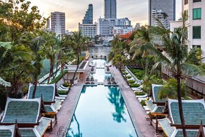 A rooftop pool with lounge chairs and palm trees, surrounded by high-rise buildings. - The Peninsula Bangkok (Bangkok)