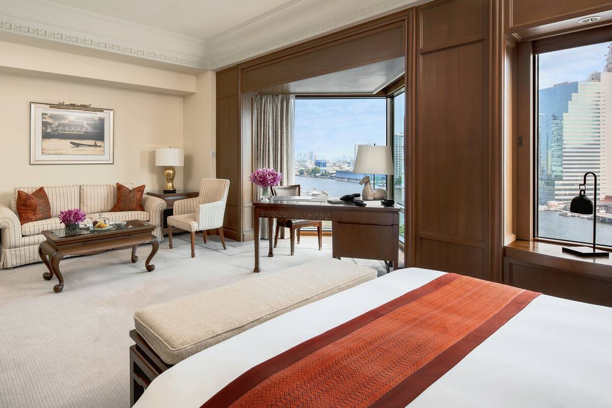 Ein Hotelzimmer mit einem großen Bett, einem Schreibtisch, einem Sessel und einer Aussicht auf die Stadt.