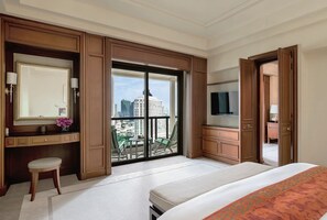 Una habitación de hotel con una cama grande, televisión, escritorio con silla, tocador con espejo y balcón con vista a la ciudad.